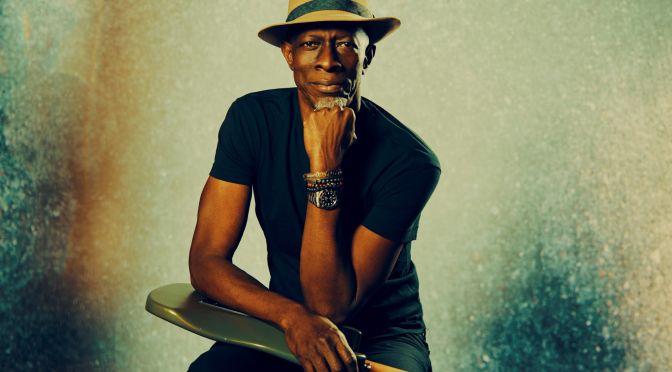 keb mo resting head on hand holding guitar