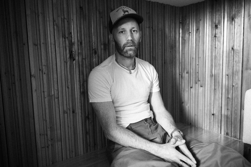 mat kearney in white t-shirt sitting on bench looking forward